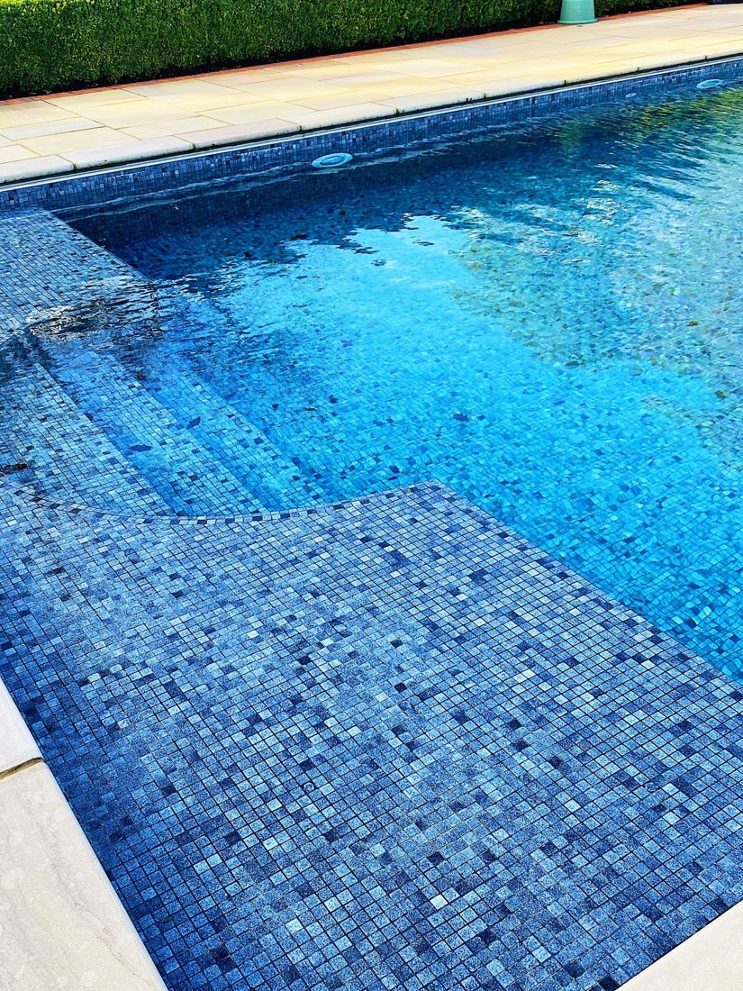 Clear blue mosaic-tiled pool with stone surround